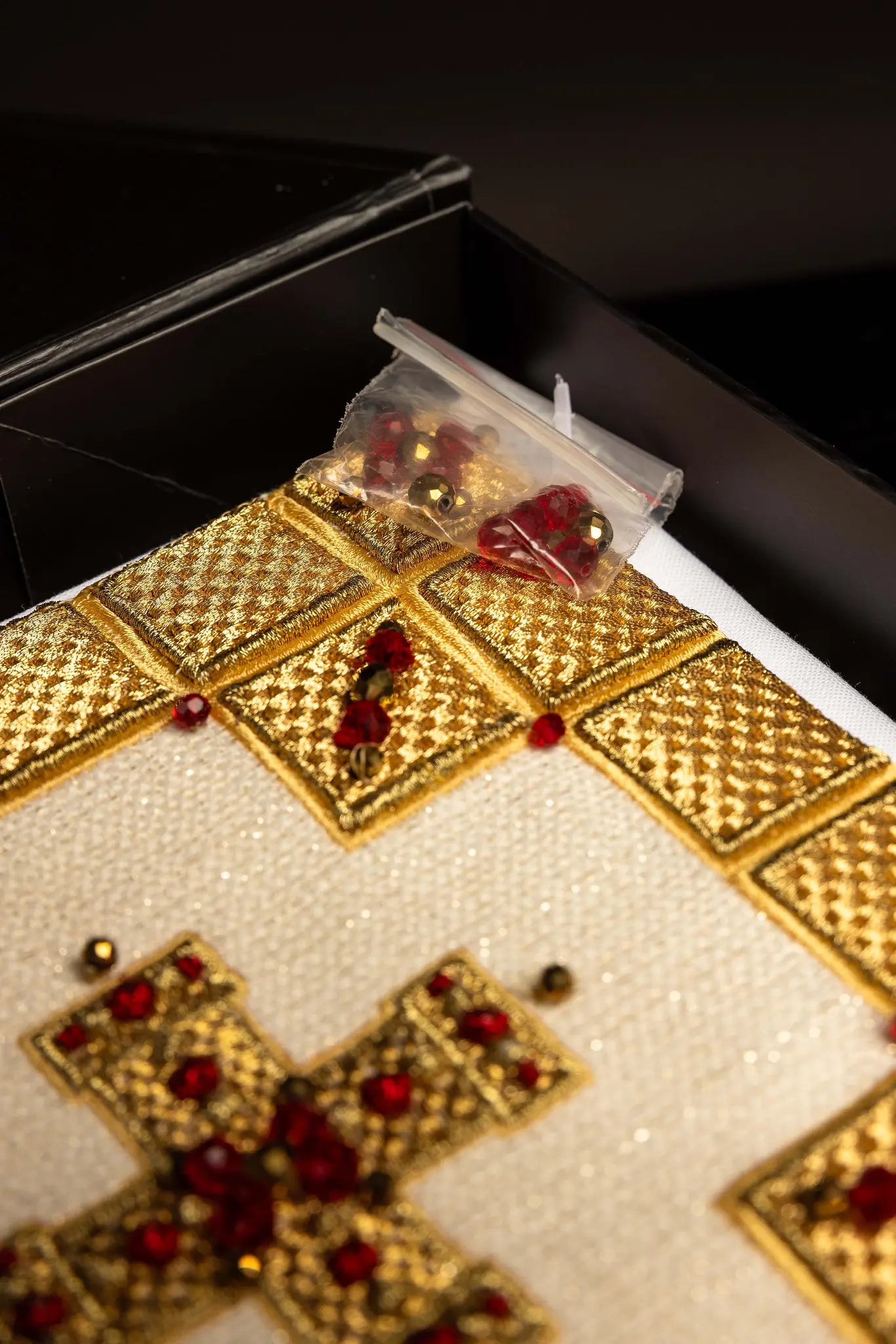 Ecru handmade chalice linen set with a pall featuring a dimensional gold cross, red hematite, and shimmering crystals, a corporal with a central cross, and a purificator and lavabo towel with embroidered crosses, all with scalloped edges.