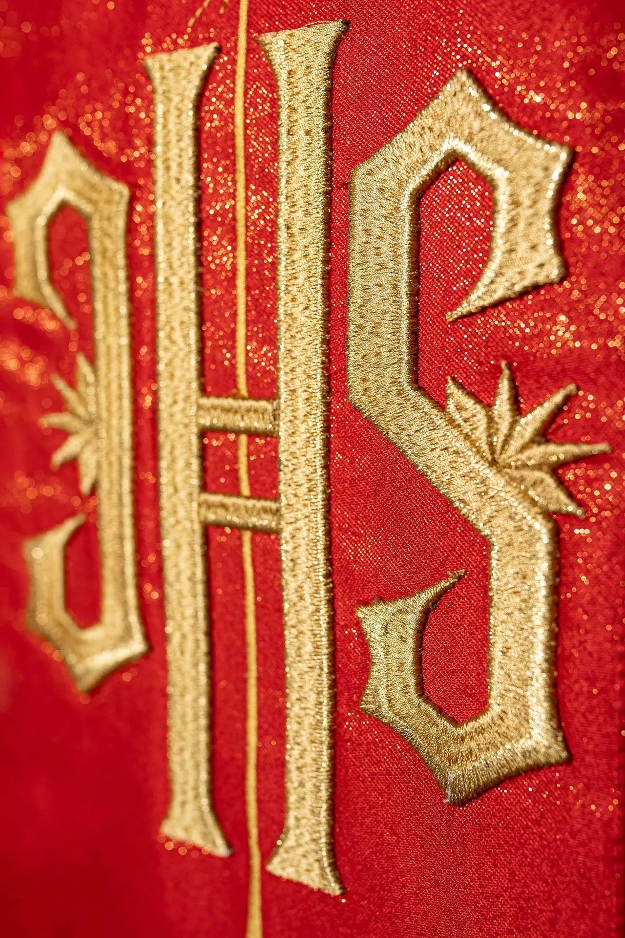 Red chasuble richly decorated with a gold motif and a wide IHS band