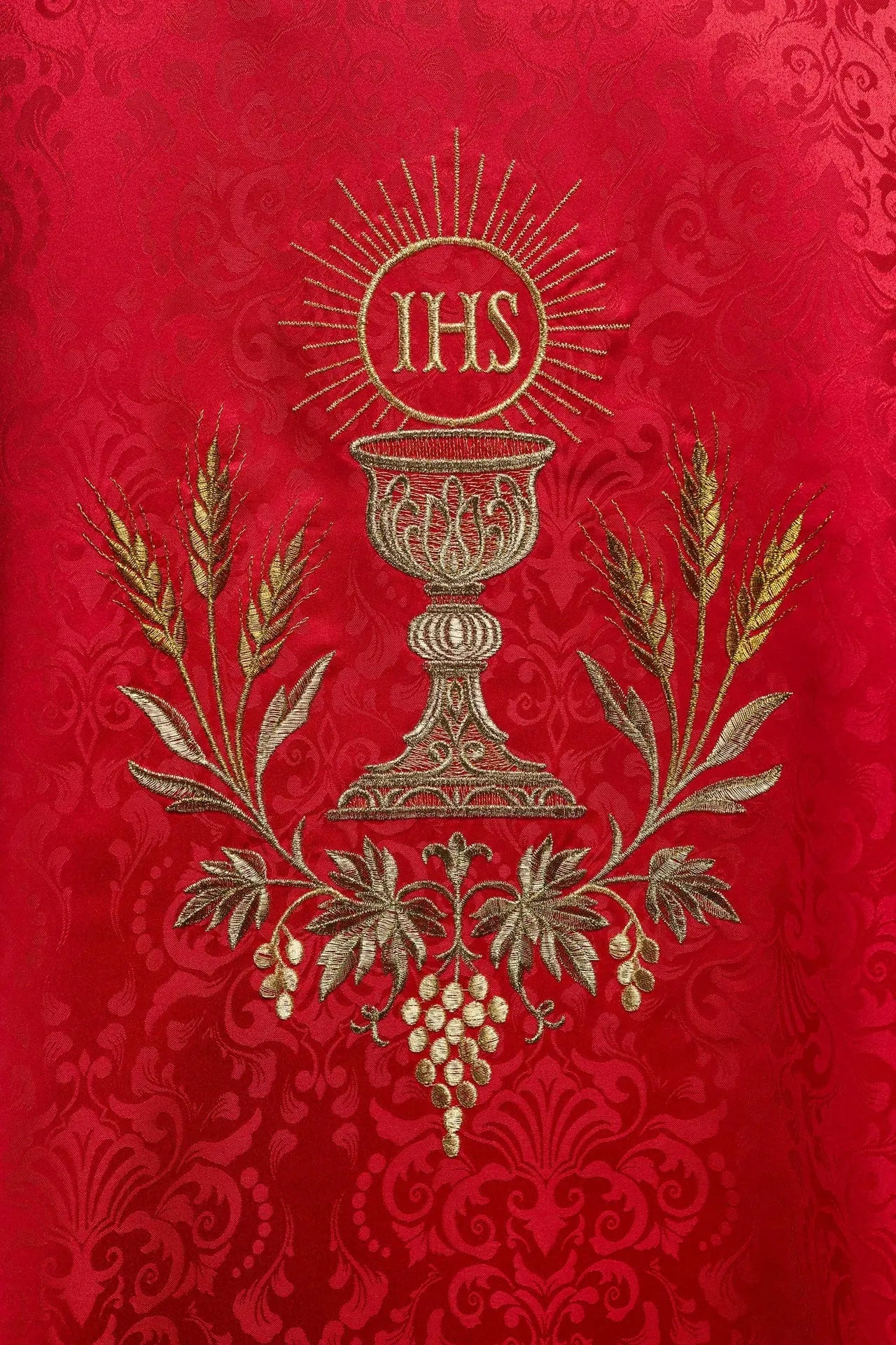 Red liturgical chasuble with an embroidered chalice and host on jacquard fabric