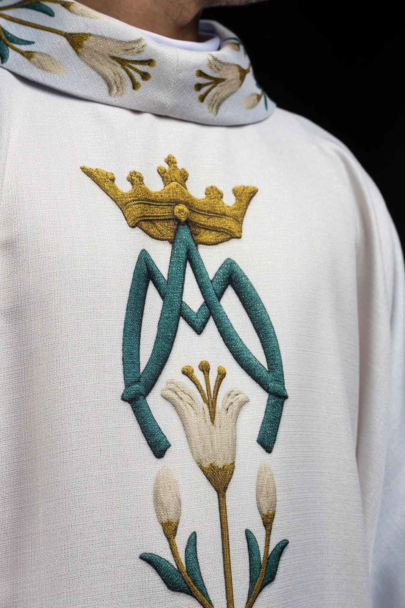 Casulla impresa mariana con patrón de lirios y monograma azul–crudo