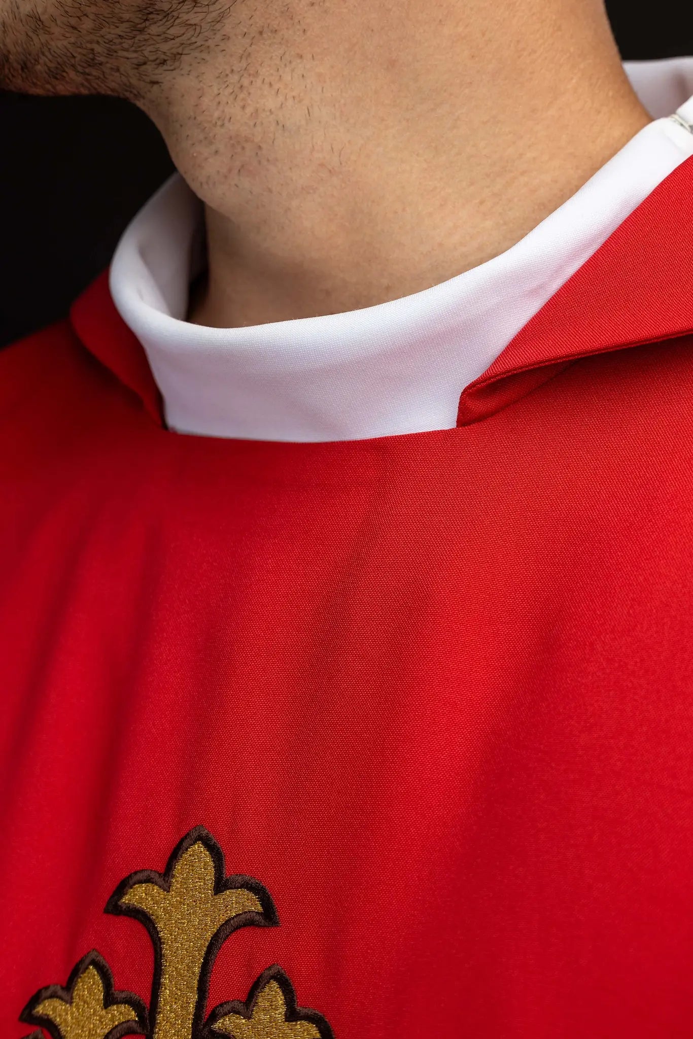 Red chasuble with gold IHS embroidery on the front and back, finished with gold trim and a V-neckline.