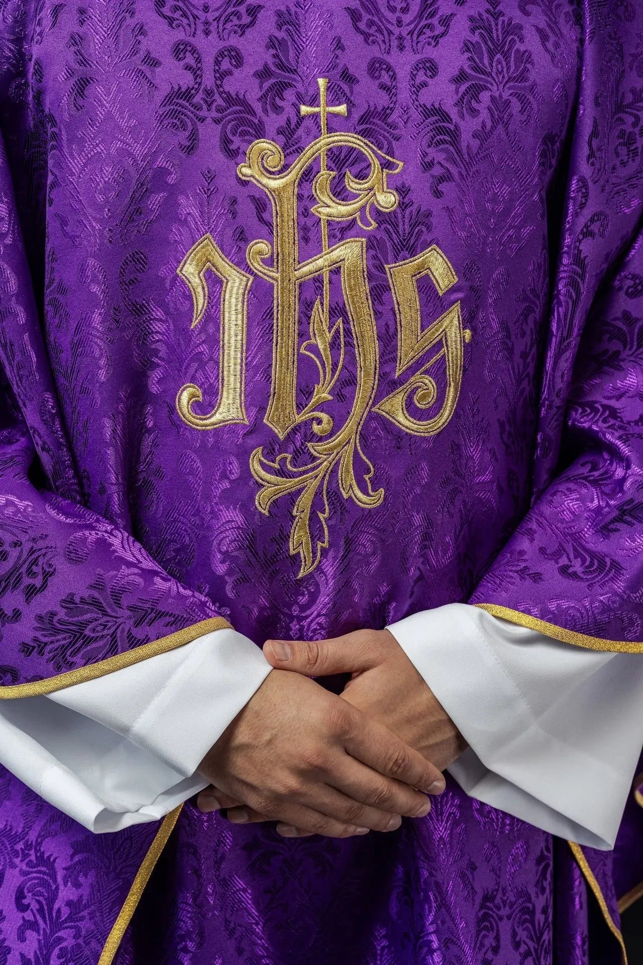 Purple chasuble with embroidered IHS motif on decorative fabric