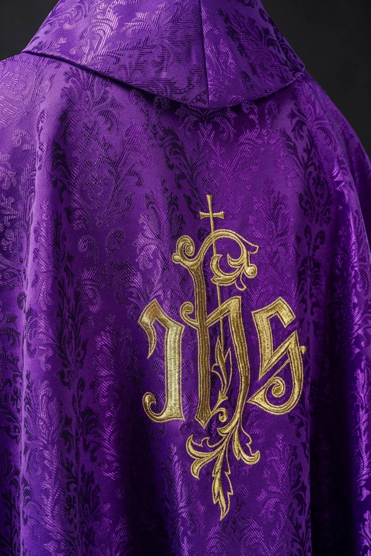 Purple chasuble with embroidered IHS motif on decorative fabric