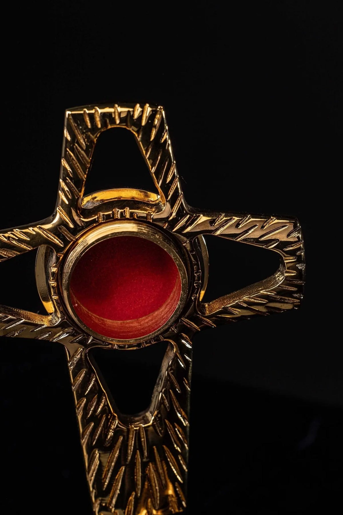 Relicario de latón dorado con centro rojo, primer plano frontal