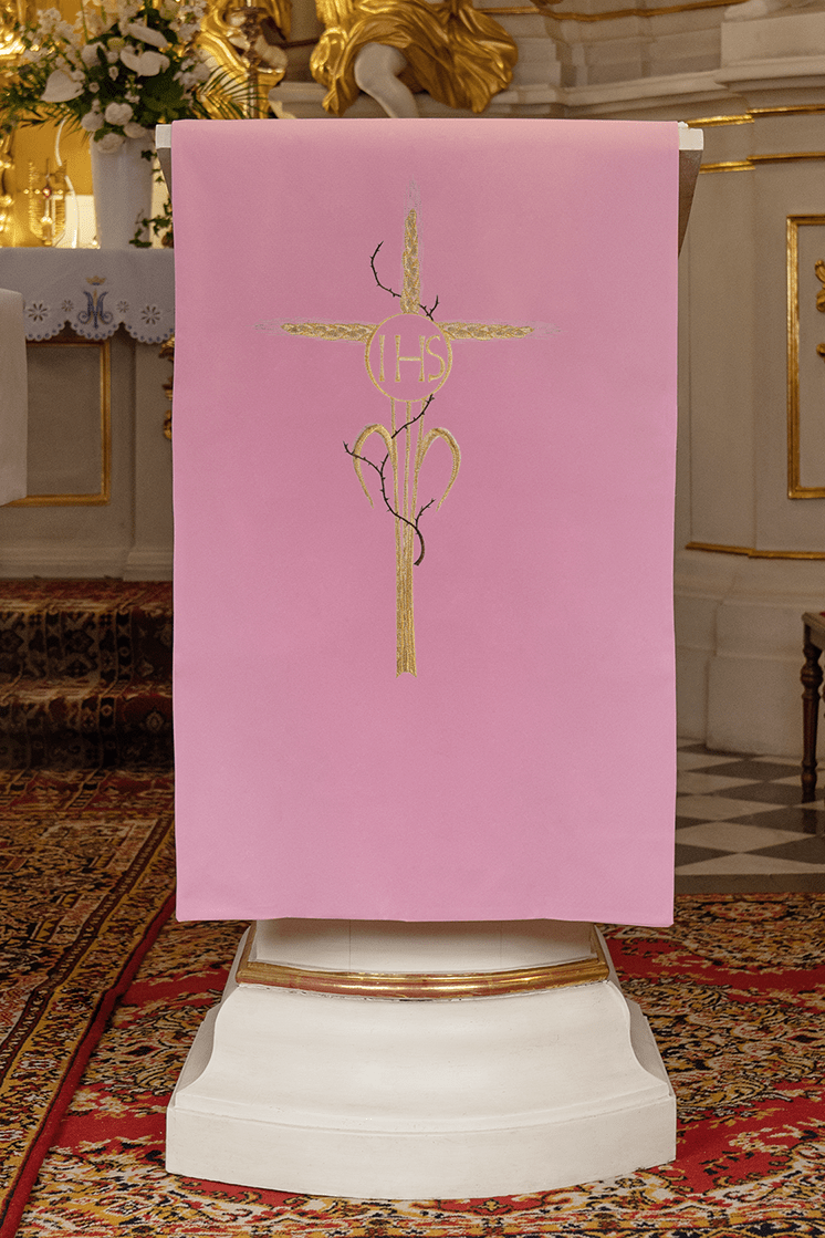 Różowa serweta na lektorium z złotym haftem krzyża