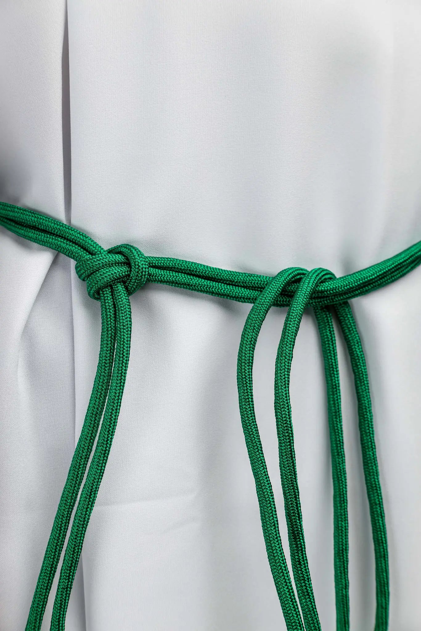 Green liturgical cincture with decorative tassels, made from braided cord.