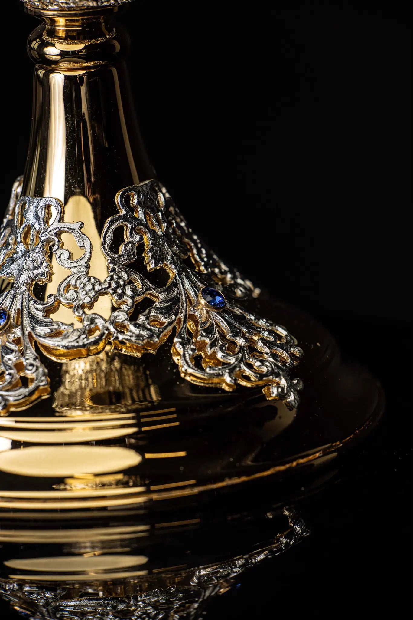 Handmade gold-plated liturgical chalice with silver-plated floral ornamentation and blue sapphire-like stones. The chalice features a decorated cup, nodus, and base.
