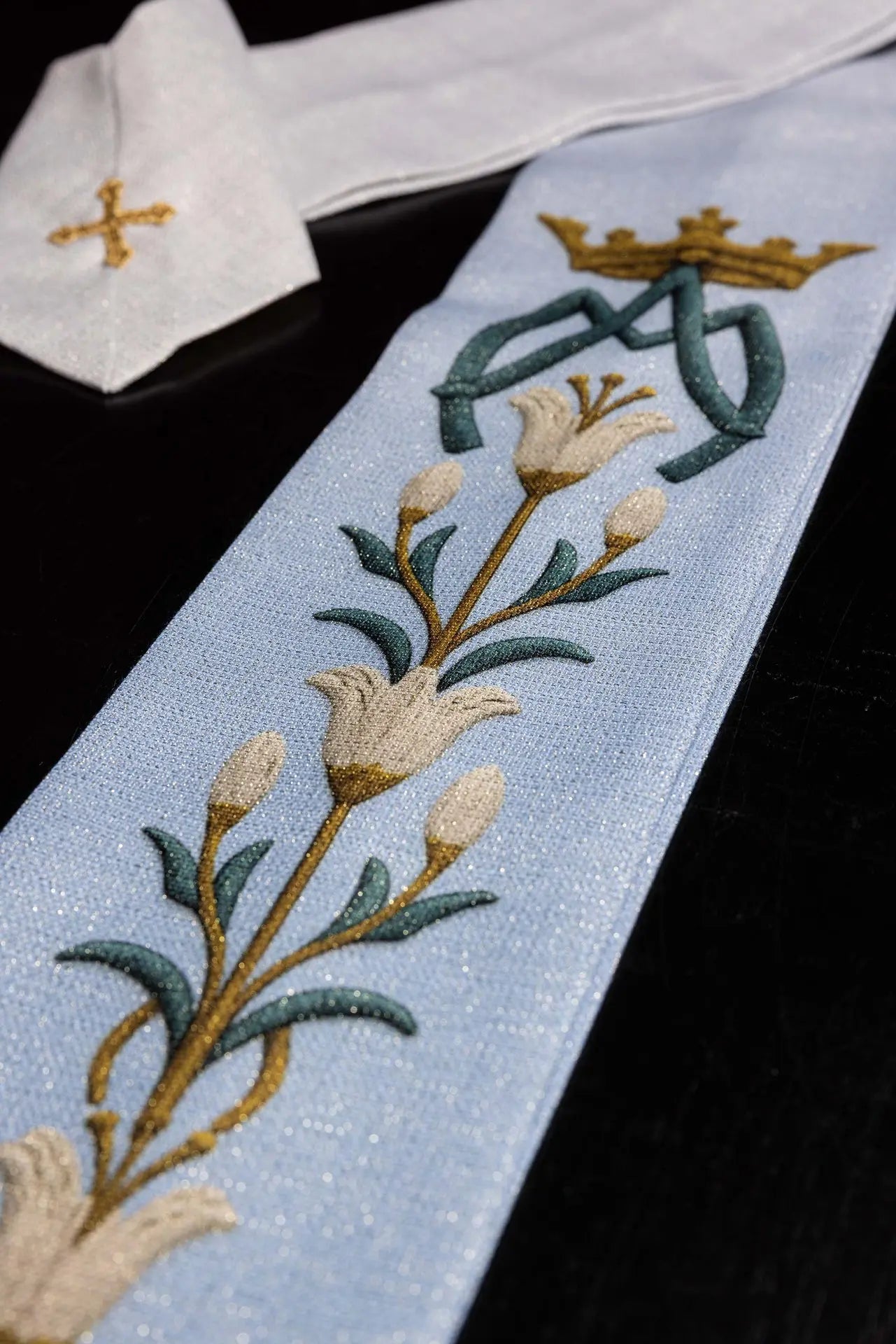 Casulla impresa mariana con patrón de lirios y monograma azul–crudo