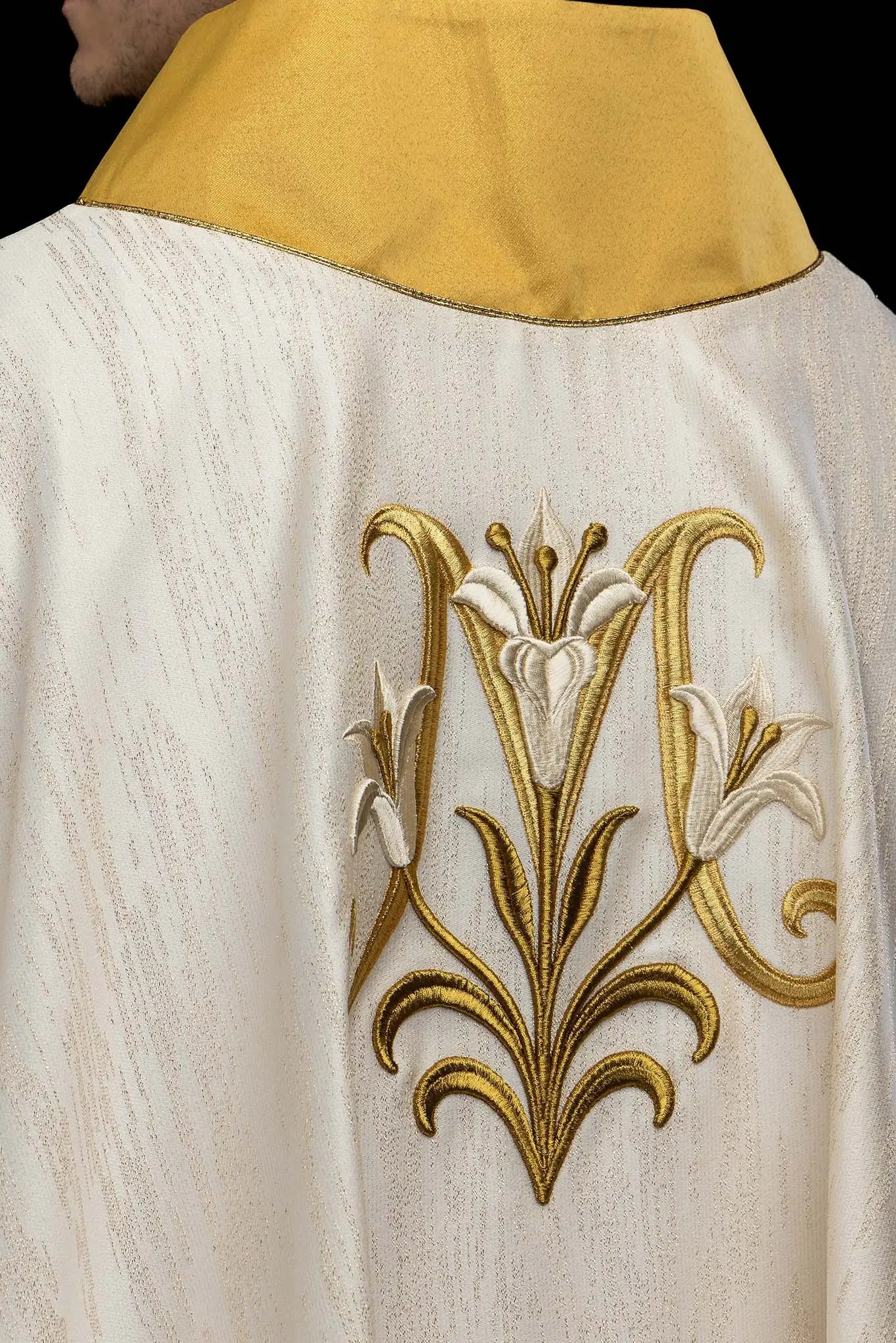 Ecru chasuble with Marian lily embroidery, gold collar, and gold trim.