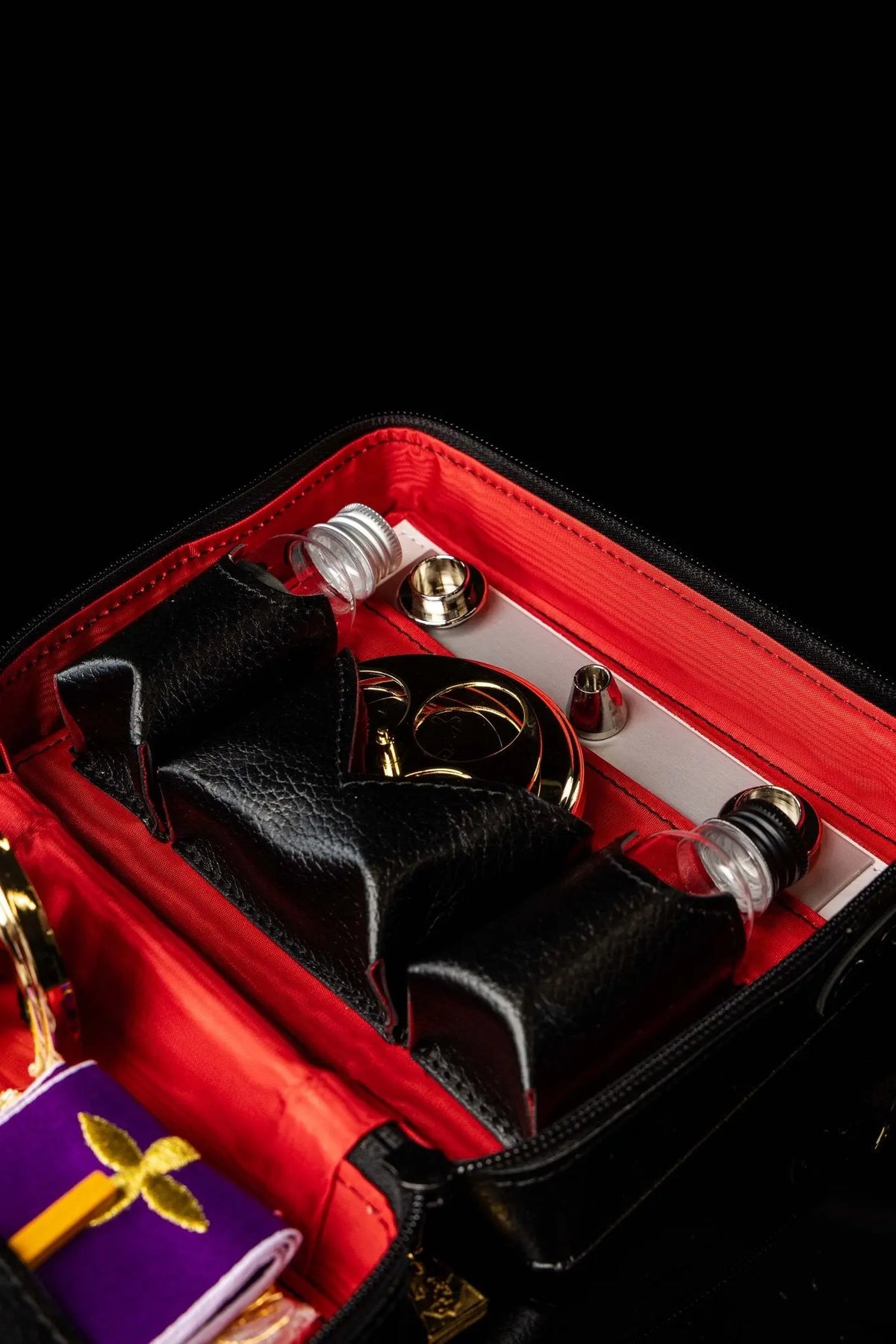 Maletín negro con equipamiento litúrgico, detalle de recipientes y accesorios