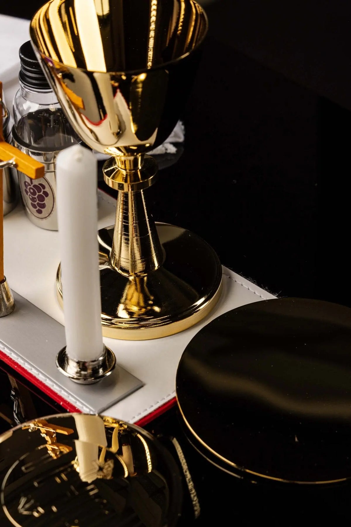 Maletín negro con cáliz, recipientes y velas, detalle lateral