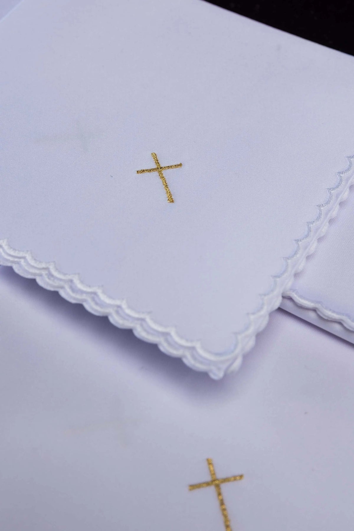 Blanco corporal con cruz bordada en dorado y borde festoneado, detalle