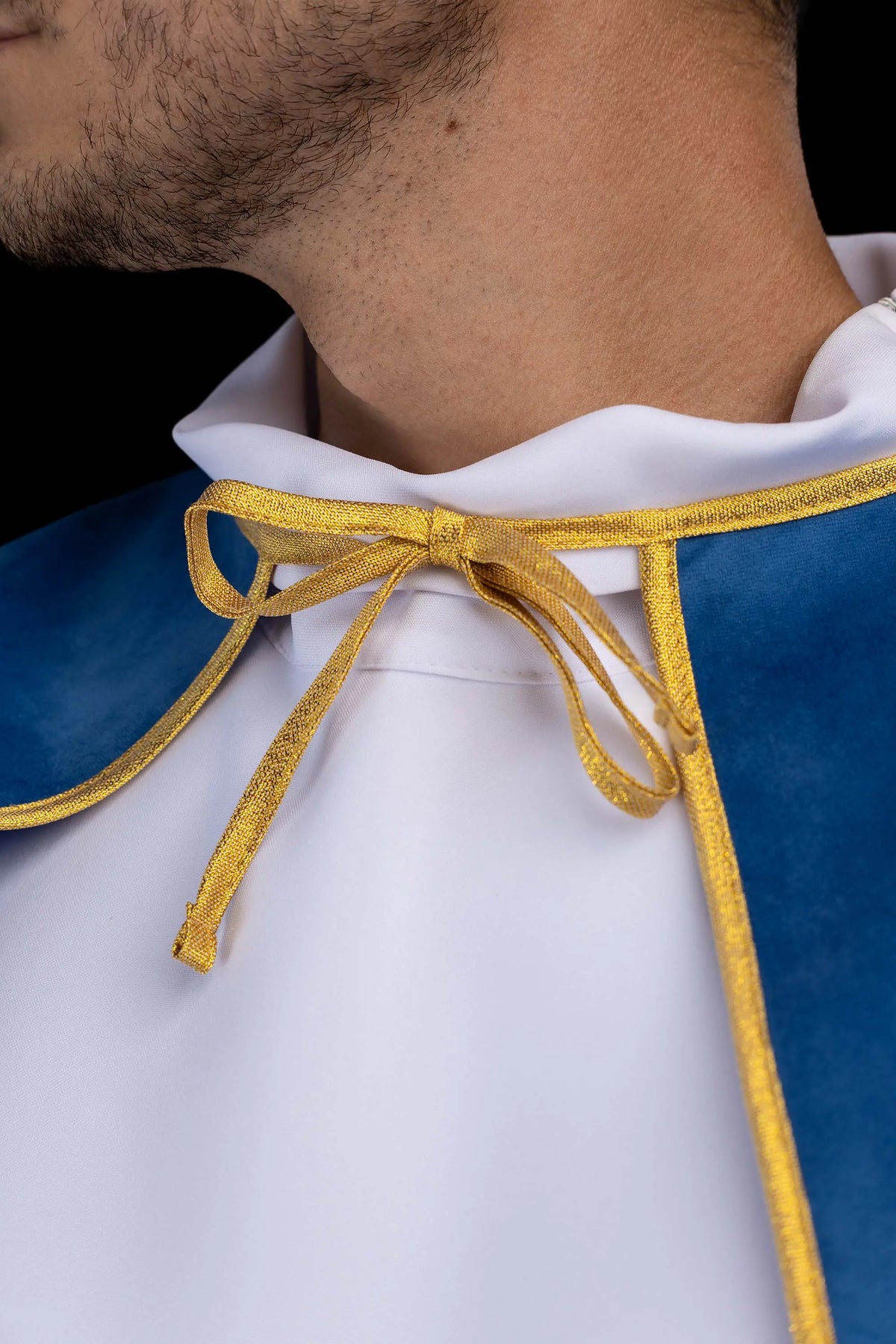 Azul capa de monaguillo de terciopelo, primer plano del cuello y lazo dorado