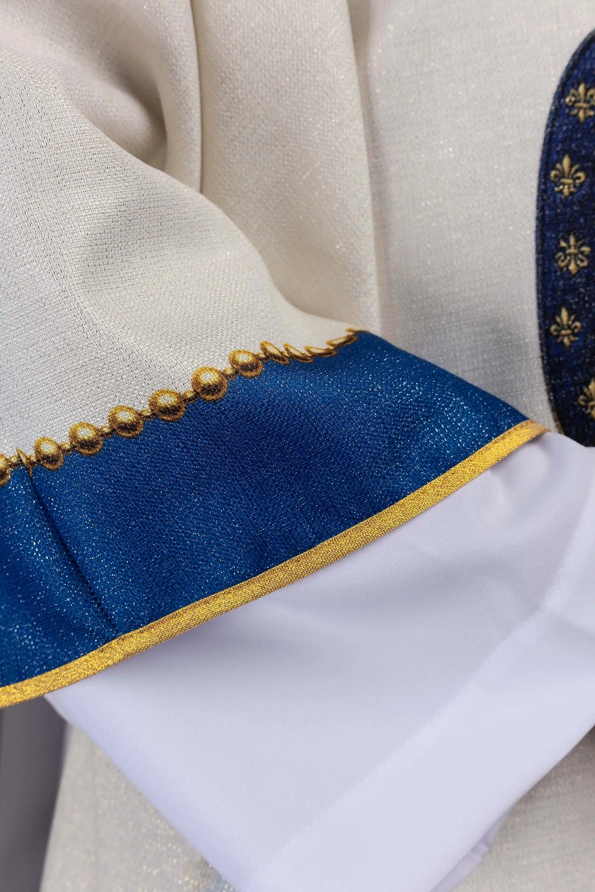 Marfil casulla con ribete azul y pasamanería dorada, detalle de manga