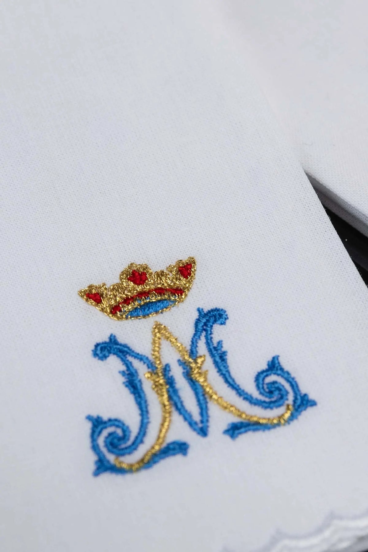 Blanco purificador con motivo mariano bordado en dorado y azul, detalle