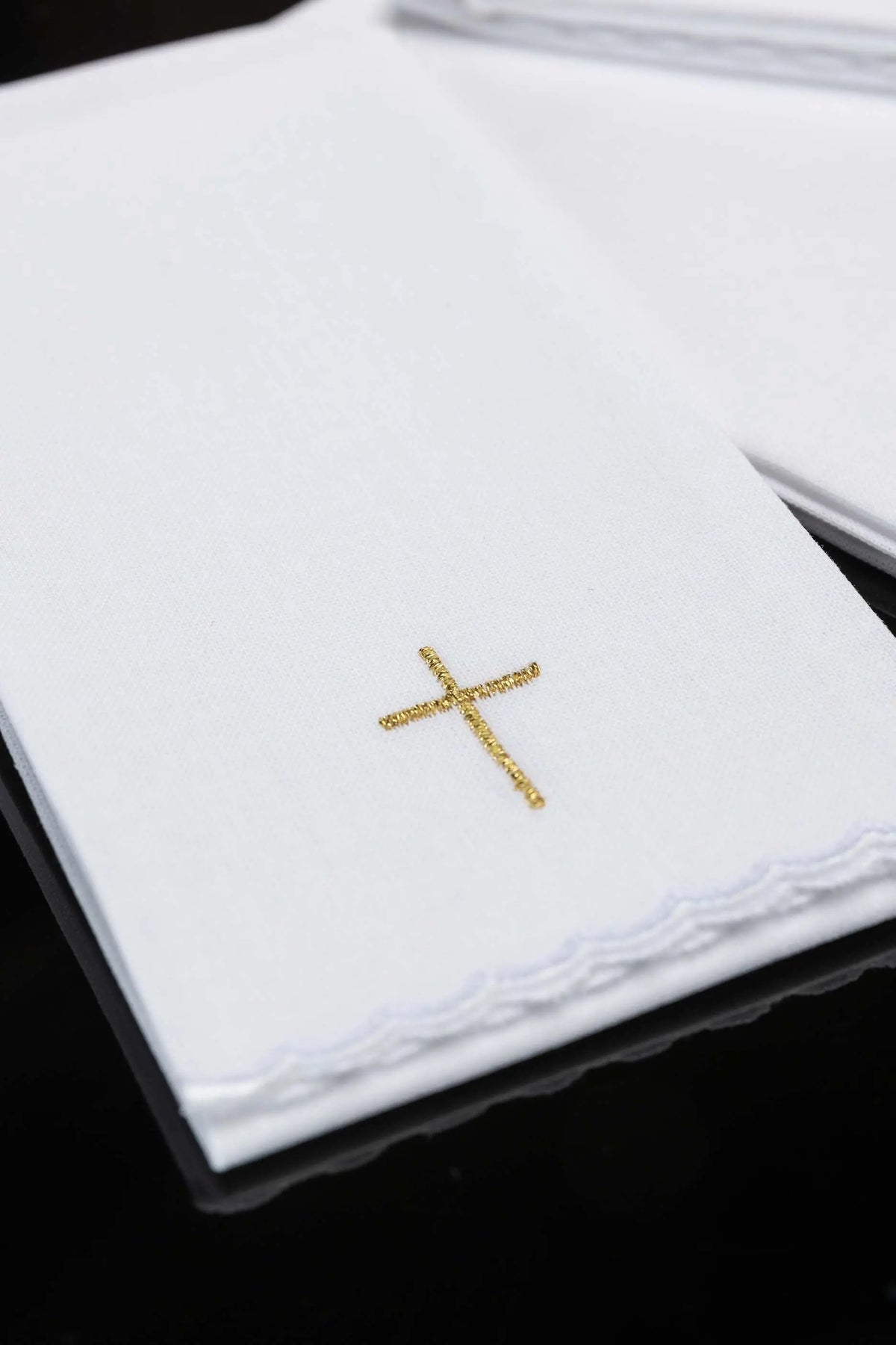 Blanco purificador con cruz bordada en dorado, detalle del bordado y el remate