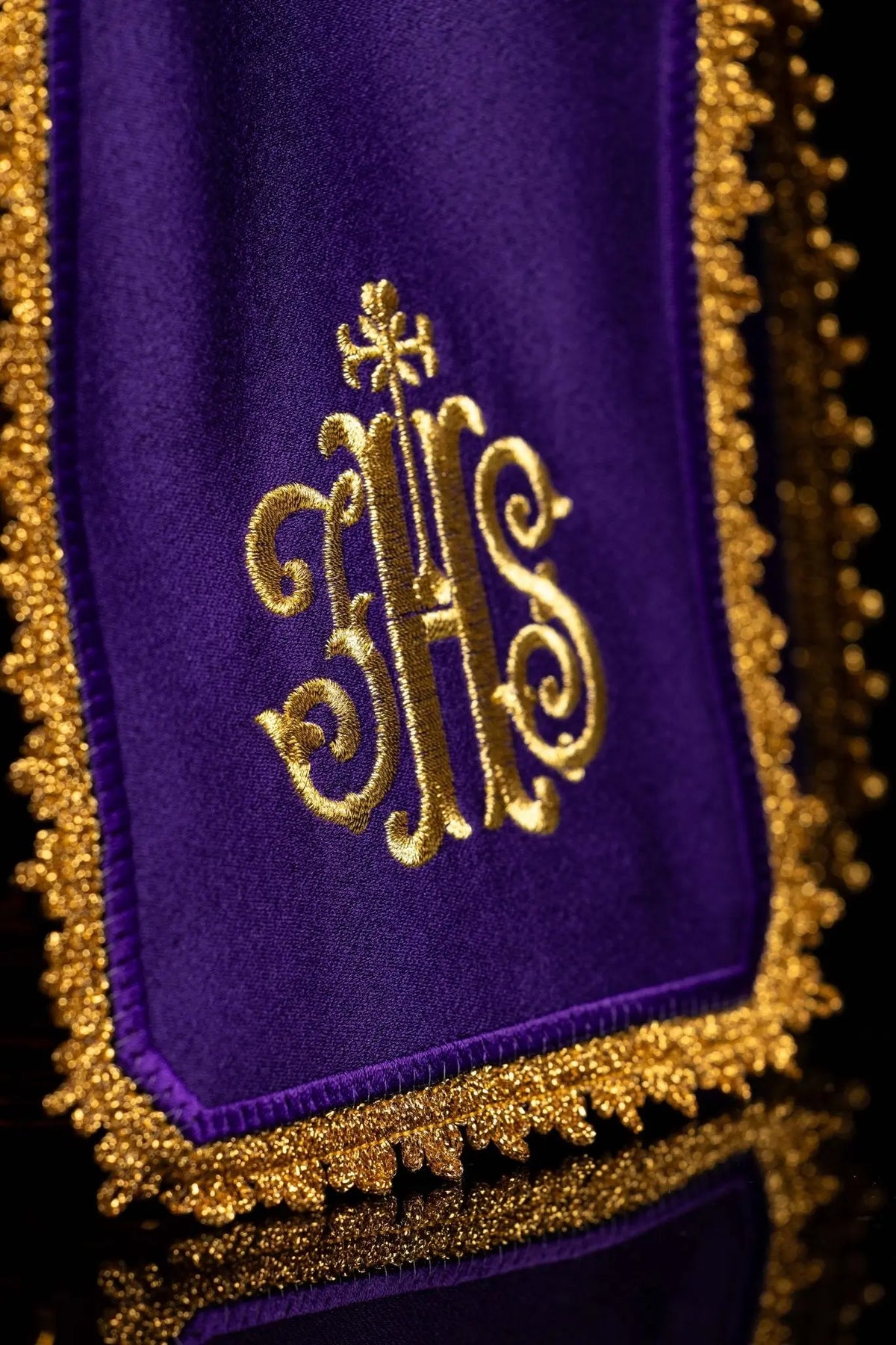 Morado cubrecopón con bordado IHS dorado, detalle del bordado y del ribete