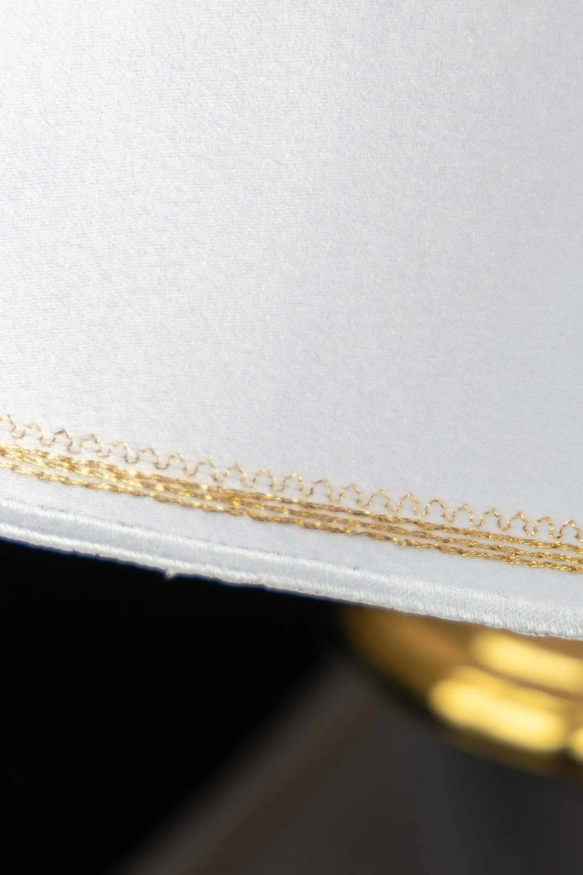 Blanco cubrecopón con bordado dorado en el borde, primer plano