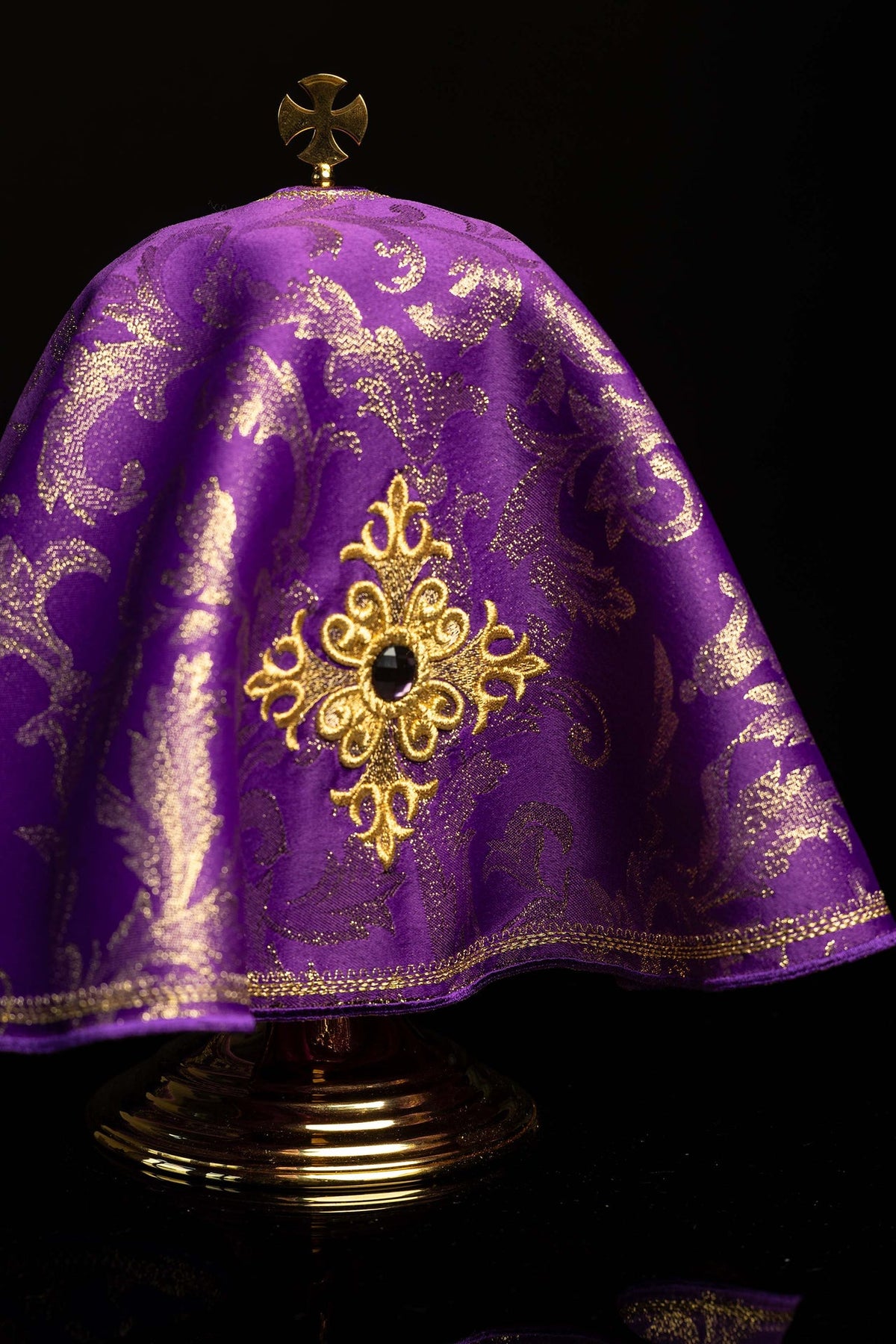 Cubrecopón morado con cruz bordada dorada, vista frontal cercana