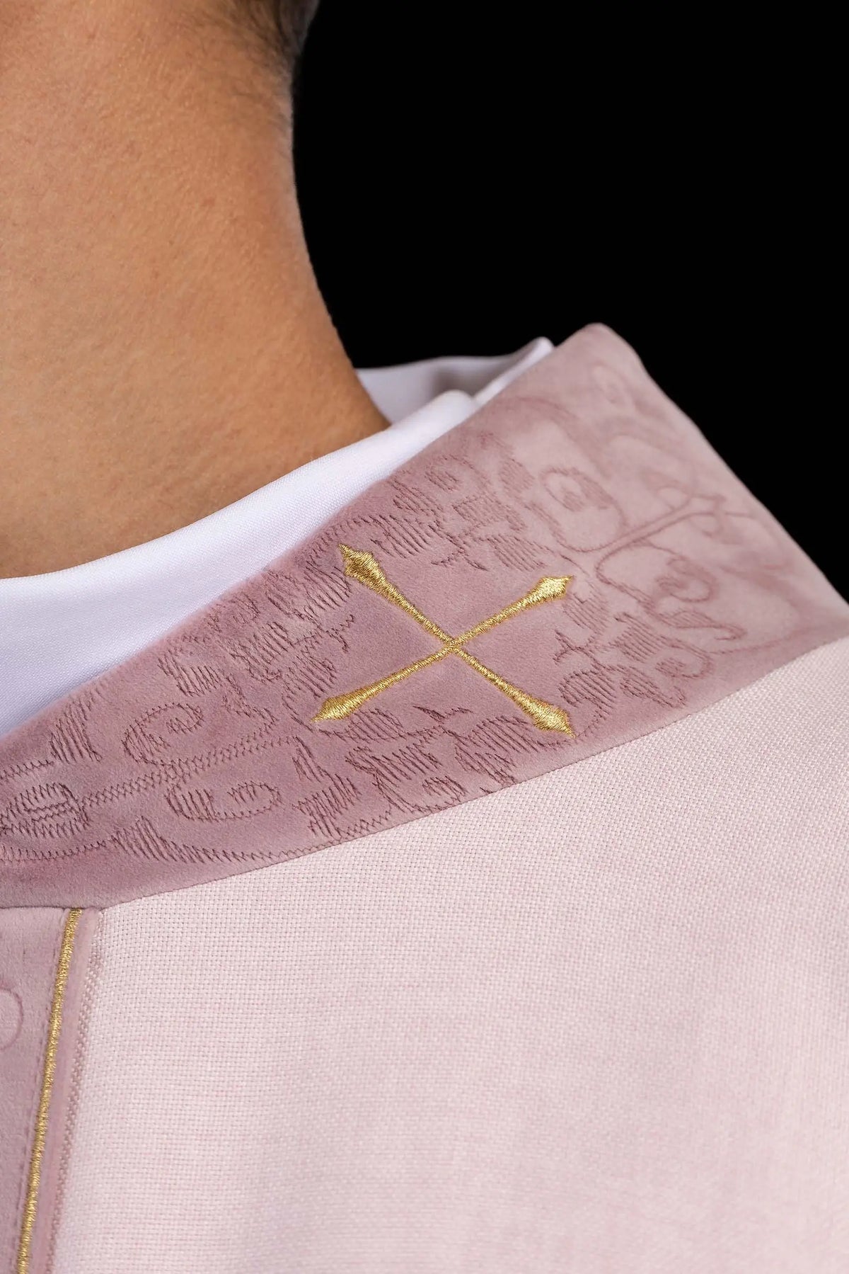 Rosa casulla litúrgica con galón central bordado y cruz dorada, detalle del cuello