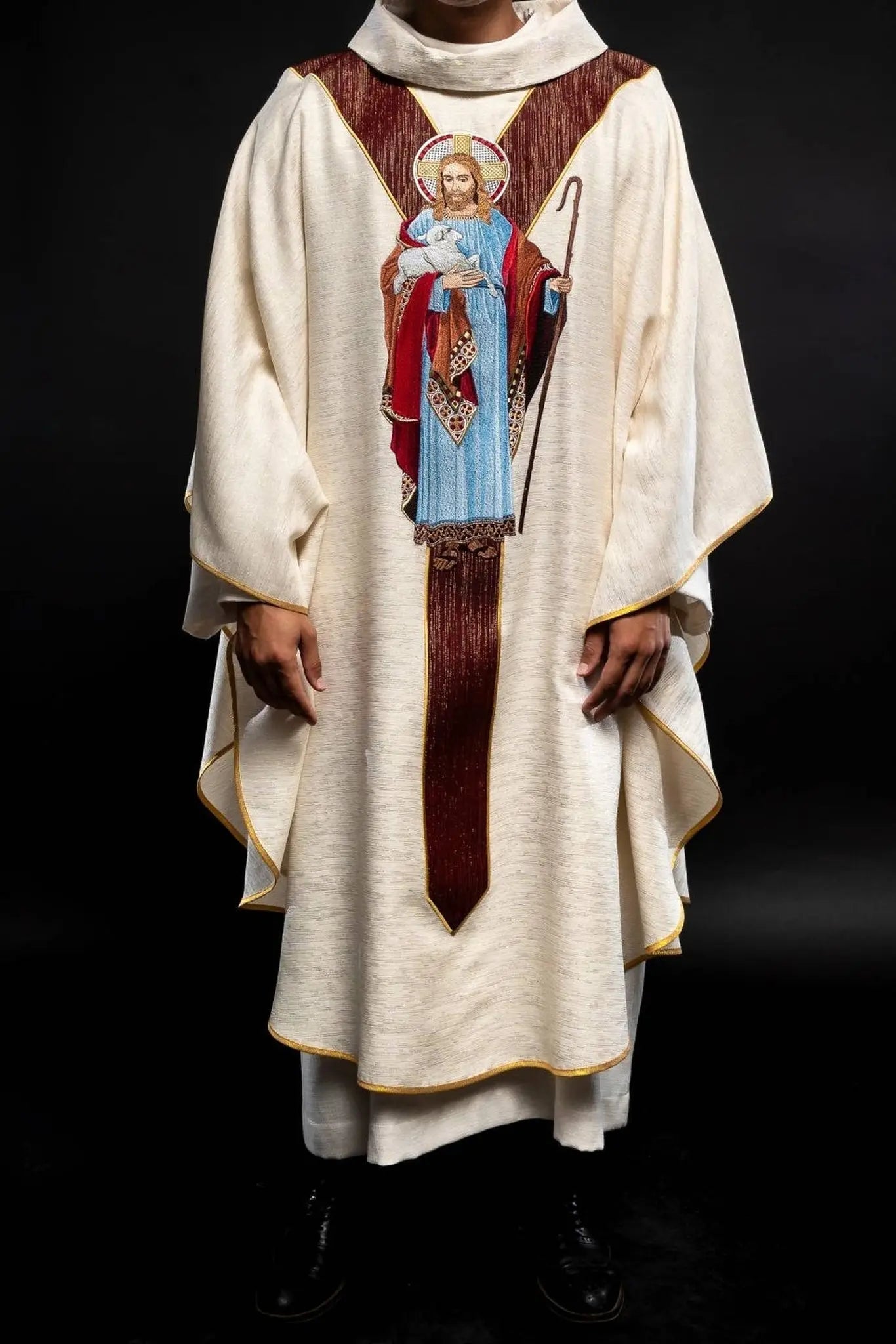 Casulla ecru con la imagen de Jesús el Buen Pastor con una franja decorativa burdeos