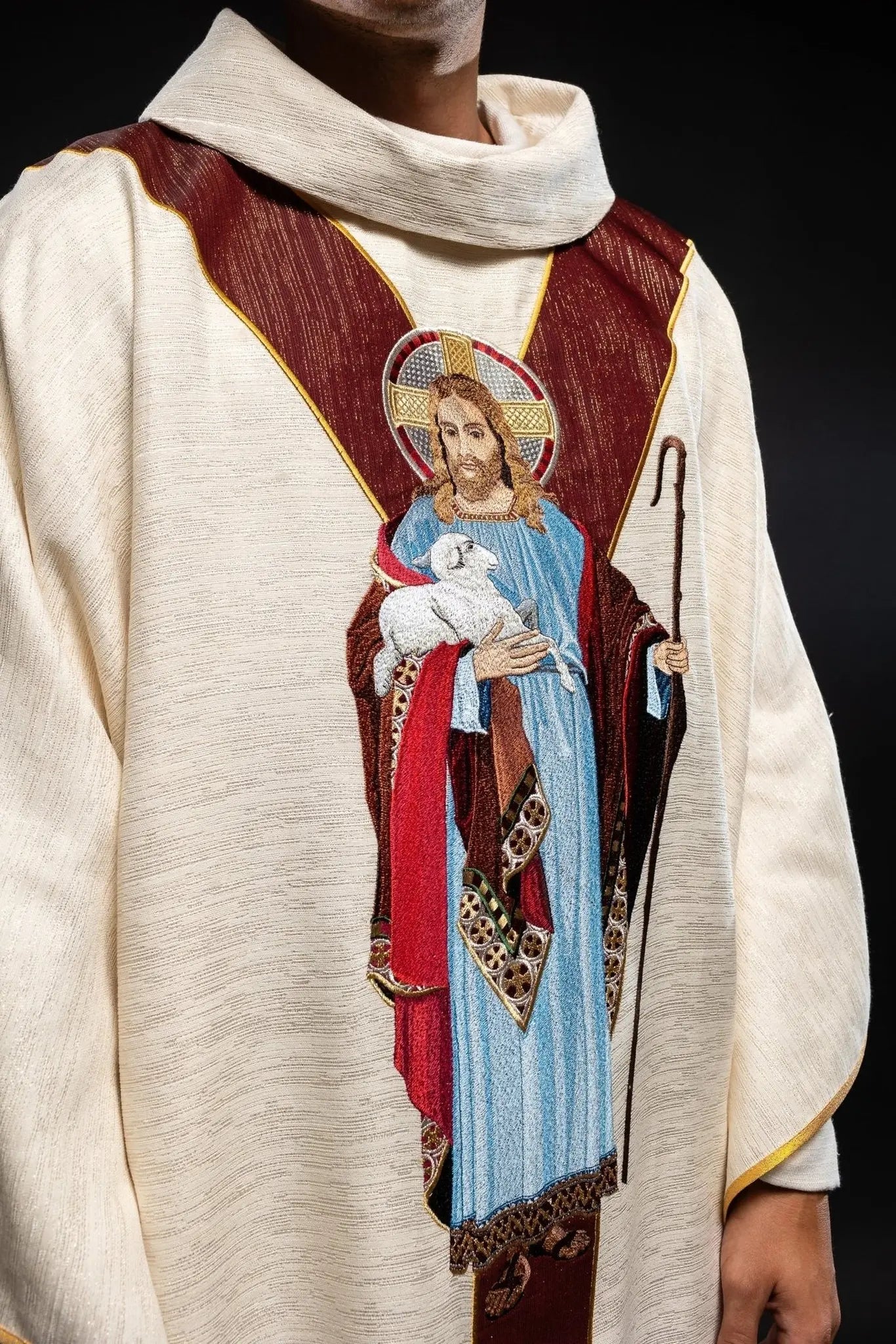 Casulla ecru con la imagen de Jesús el Buen Pastor con una franja decorativa burdeos