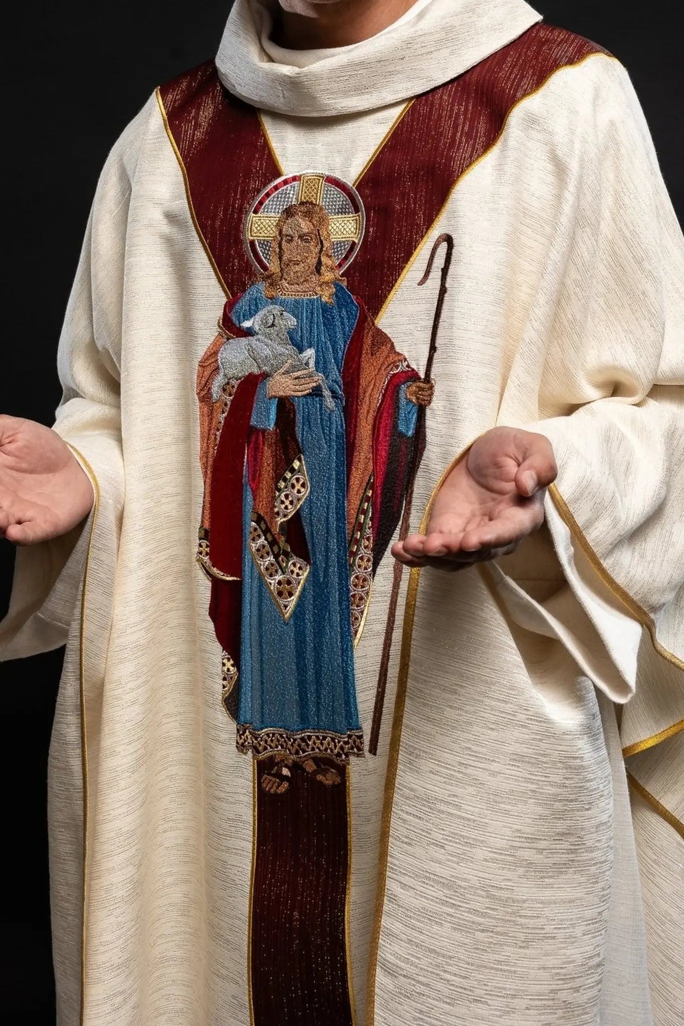 Casulla ecru con la imagen de Jesús el Buen Pastor con una franja decorativa burdeos